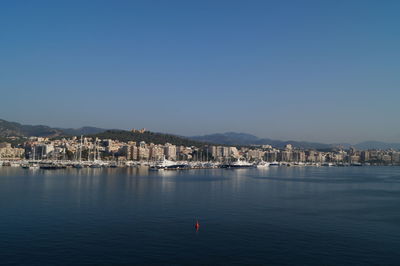 View of townscape by sea against clear blue sky