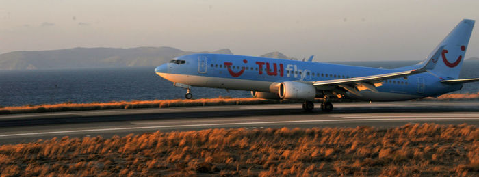 Airplane on airport runway against sky