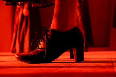 Low section of woman wearing high heels shoe on illuminated red stage