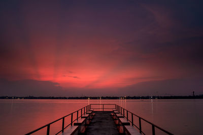 Pier over sea against orange sky