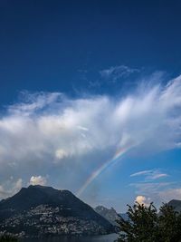 Low angle view of rainbow over mountains against blue sky