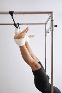 Mid adult man stretching legs on pilates machine in exercise room