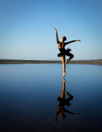 Man jumping on lake against clear blue sky