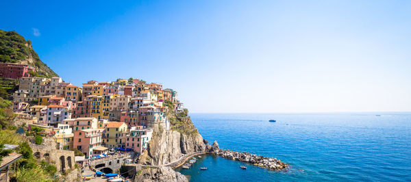 Residential district on mountain by sea against clear sky