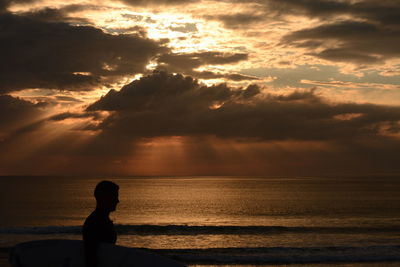 Silhouette man on beach against sky during sunset