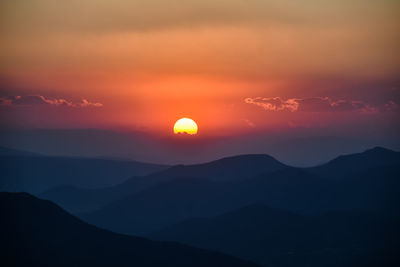 Scenic view of silhouette mountains against romantic sky at sunset