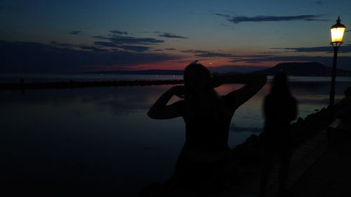 Silhouette man photographing sea against sky during sunset