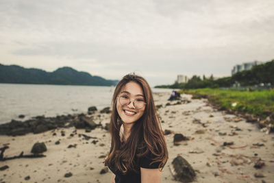 Portrait of smiling young woman standing on beach