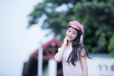 Portrait of young woman standing against blurred background