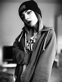 Portrait of woman wearing hat standing against wall