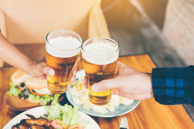 Midsection of man holding beer glass on table
