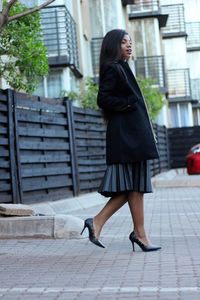 Full length side view of woman walking on footpath in city