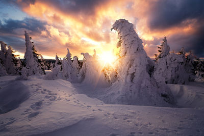 Panoramic view of snow covered land against sky during sunset