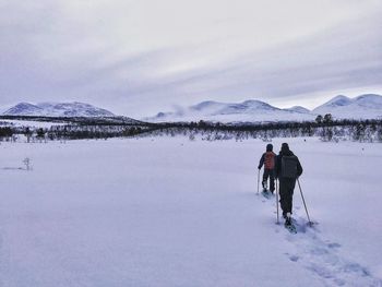 Rear view of people walking on snow covered mountain