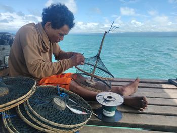 Man sitting in sea against sky