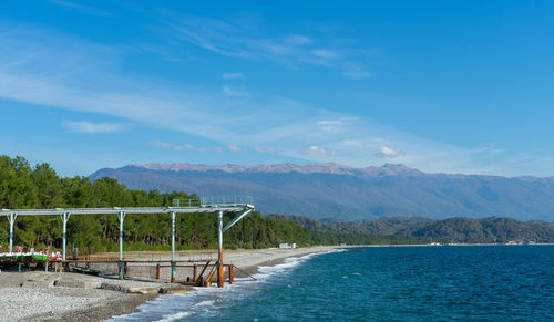 Swimming pool by sea against blue sky