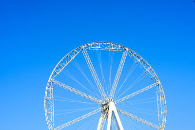 Low angle view of ferris wheel against clear blue sky