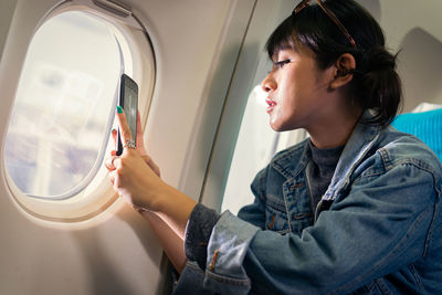 Woman photographing with phone while sitting in airplane