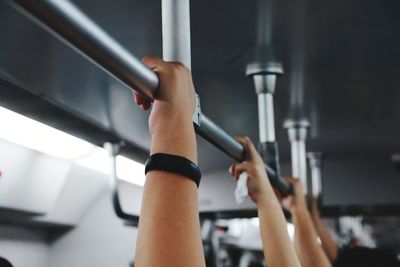 Cropped hands of people holding metallic handle in train