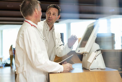 Doctors discussing by computer at hospital