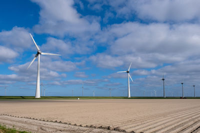 Wind turbines on field against sky