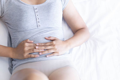 Midsection of woman touching bed