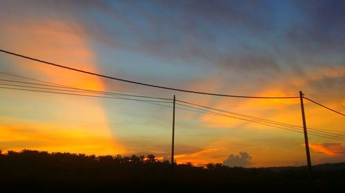 Low angle view of silhouette electricity pylon against sky during sunset