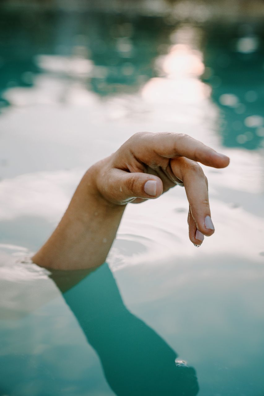 water, hand, human hand, human body part, body part, nature, finger, real people, leisure activity, one person, human finger, day, lifestyles, focus on foreground, lake, outdoors, gesturing, reflection, human limb, human arm, swimming pool, arms raised