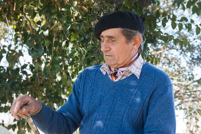 Senior man standing against tree outdoors