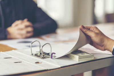 Close-up of businessman taking bribe on table at office