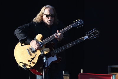 Man playing guitar against black background