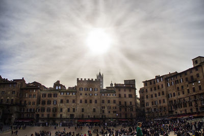 Crowd at piazza del campo against sky on sunny day in city
