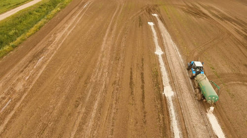 Aerial view tractor spraying the chemicals on the large green field. 