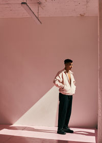 Young man looking away against wall