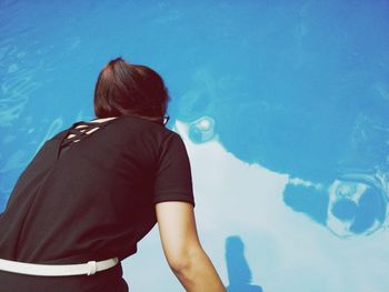 Rear view of woman standing at swimming pool