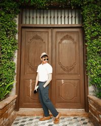 Portrait of smiling woman standing against door