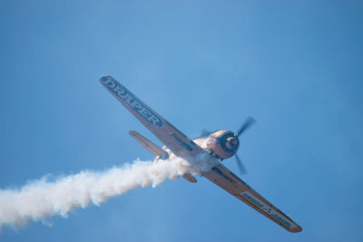 Low angle view of airplane flying against blue sky