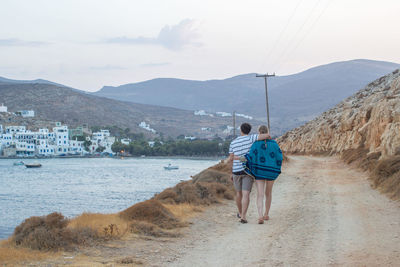 Rear view of woman walking with dog on mountain against sky