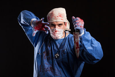 Portrait of man wearing mask against black background