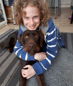 Portrait of smiling boy embracing dog at home