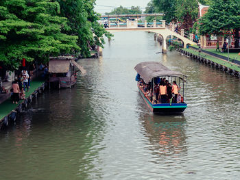 People on boats in canal along trees