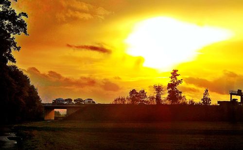 Silhouette of trees against dramatic sky during sunset