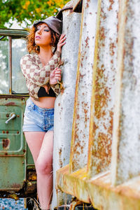 Portrait of young woman standing against wall