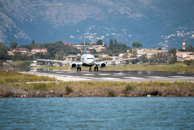 Airplane by sea against mountains