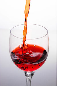 Close-up of wineglass on glass against white background
