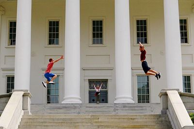 Low angle view of people jumping over steps against building