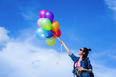 Low angle view of woman holding balloons