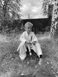 Full length of boy sitting on field