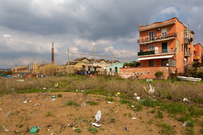 Houses on field by buildings in town against sky