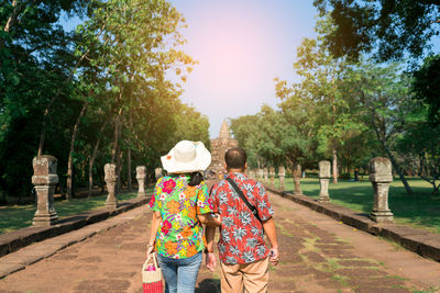 Rear view of women walking on footpath amidst trees